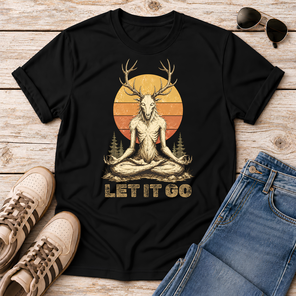 Shop the Meditating Wendigo Graphic T‑Shirt, featuring an antlered forest spirit meditating beneath a retro sunset. Perfect for cryptid fans, folklore lovers, and forest weirdos. 🦌🔮